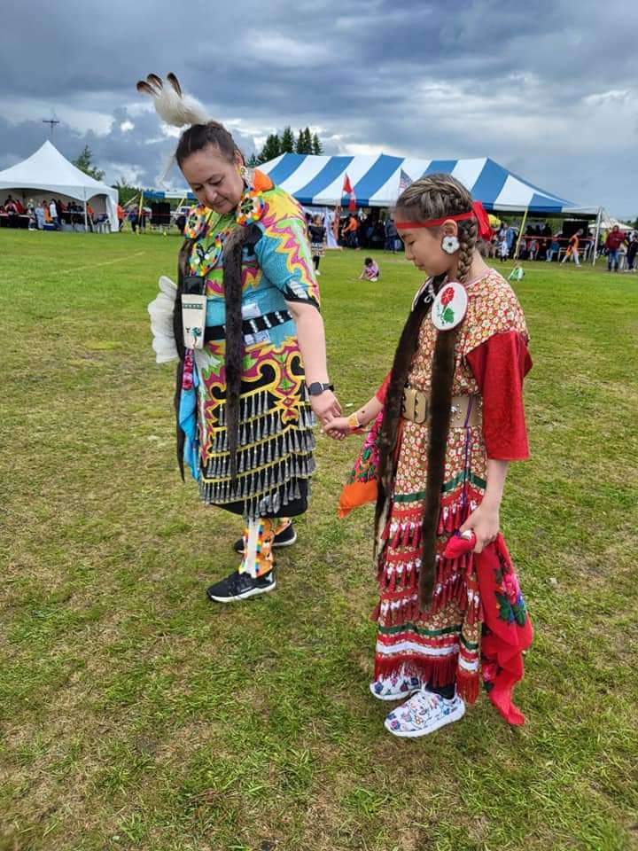 La photo présente Annick Wylde avec sa nièce. Toutes deux portent les habits de danse tradictionnels abitibiwinni et se tiennent par la main. Ces habits sont issus des méthodes de l'artisanat ancestral. 